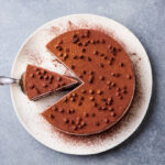 Tiramisu cake with chocolate decotaion on a plate. Grey stone background. Top view.
