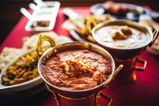 Indian feast with butter chicken, chicken tandoori, lamb curry, vegetable curry, samosas, pakoras, bhajis, naan bread and basmati rice on a table. North Indian food